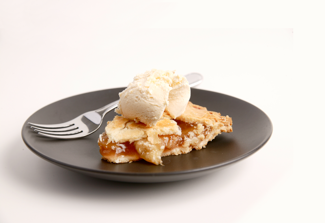 A slice of pie with ice cream on a dark plate